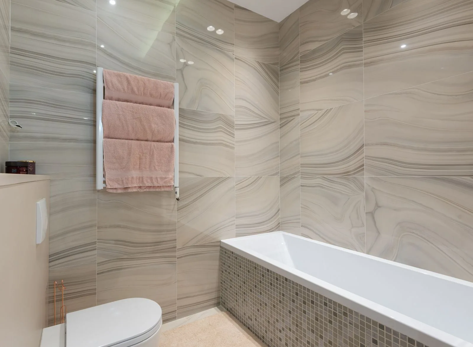 Modern bathroom with towels hanging on a wall rack next to the bathtub